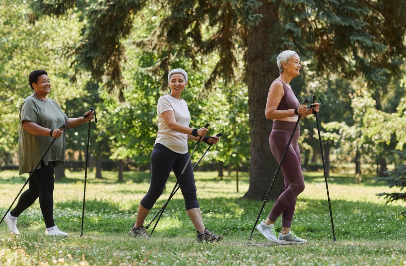 Three seniors use walking sticks to support their joints while going on a casual walk near their senior living community