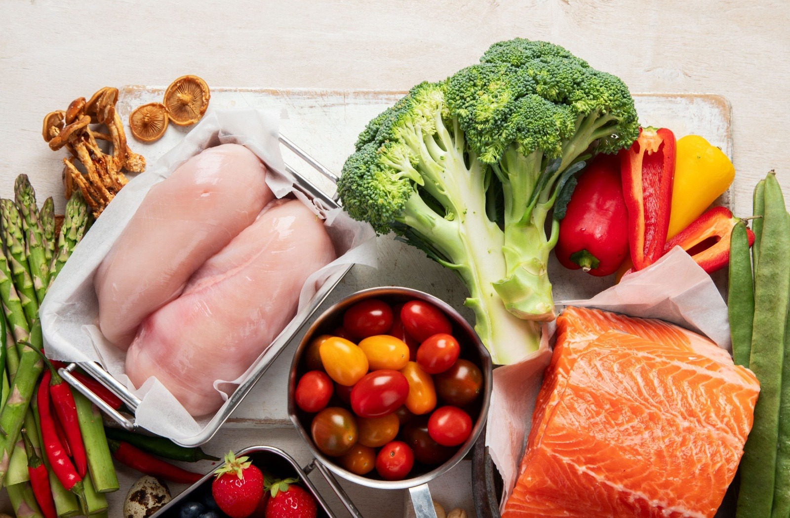 A display featuring a selection of keto diet staples, such as salmon, broccoli, tomatoes, chicken breast, mushrooms, and more.