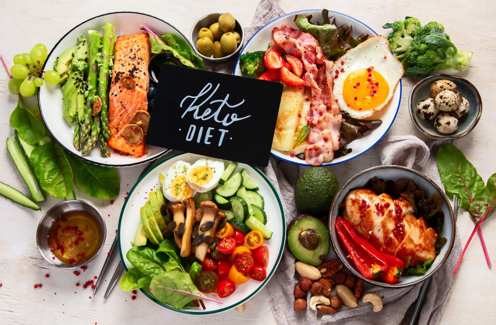 A selection of keto diet staples, including fish, veggies, eggs, more fresh, brightly-colored food with a sign that says, "keto diet."